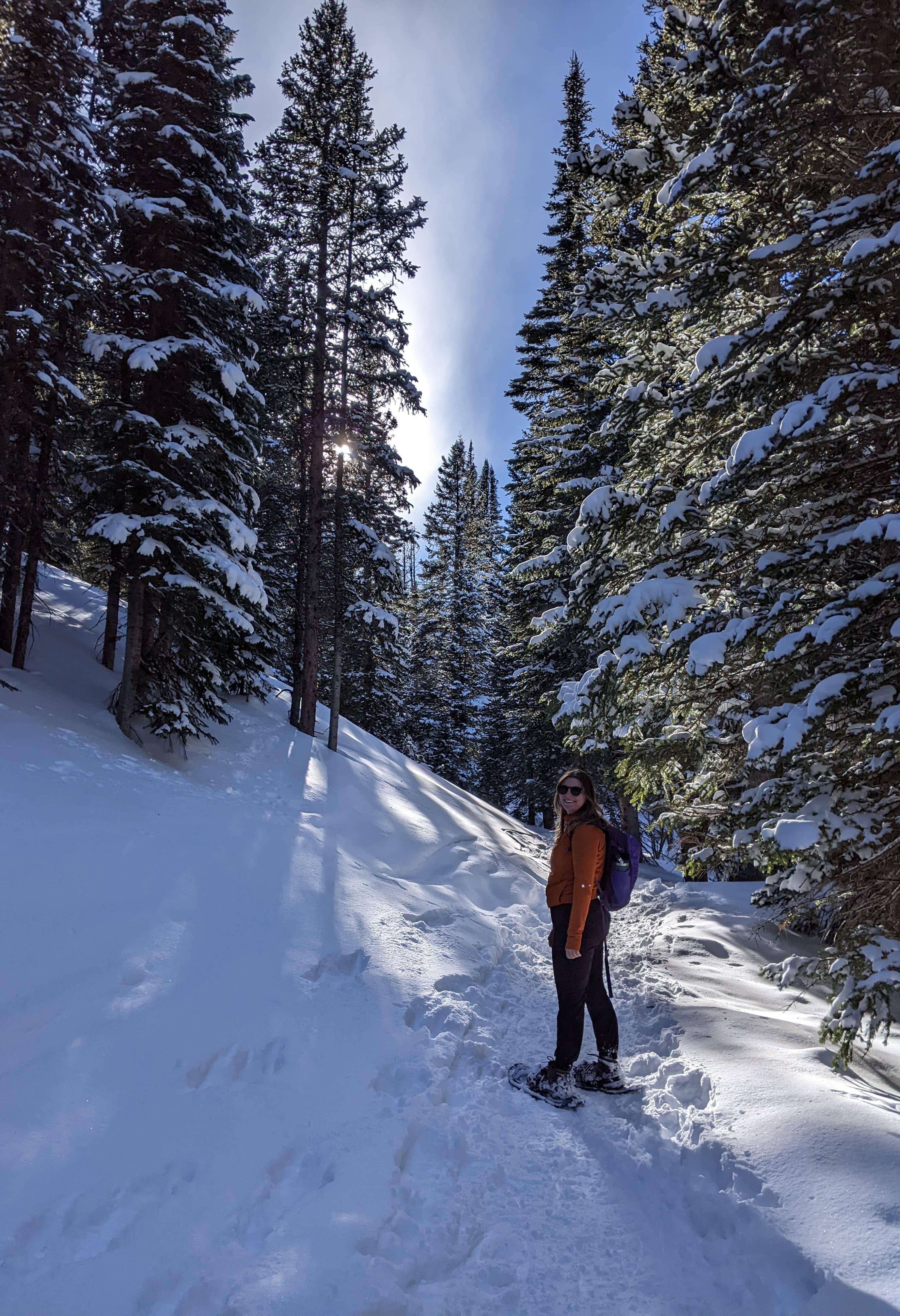 Martha Carter somatic therapist denver snowshoeing in a forest on a sunny winter day